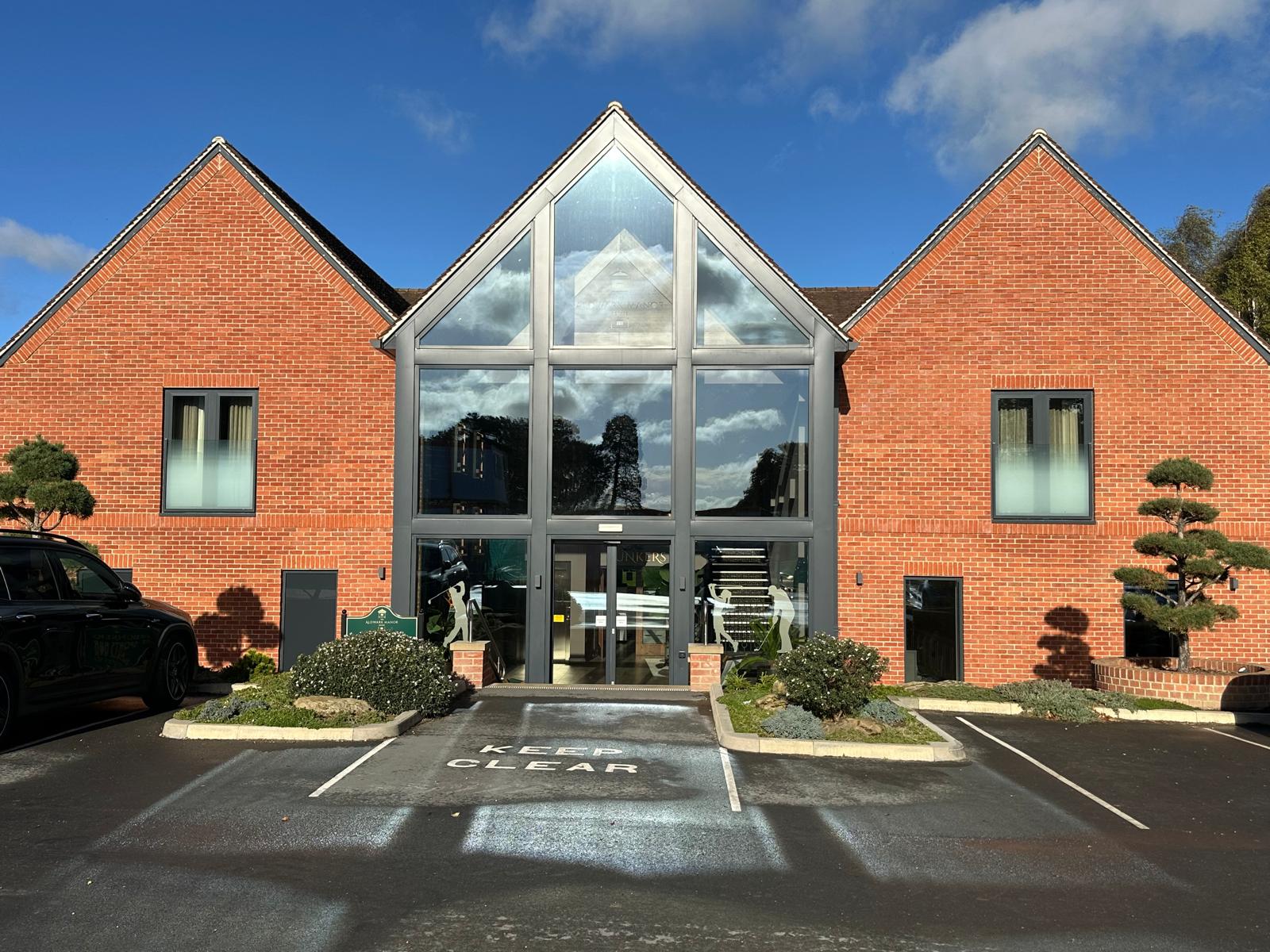 Glazed gable entrance between brick wings at Aldwark Manor